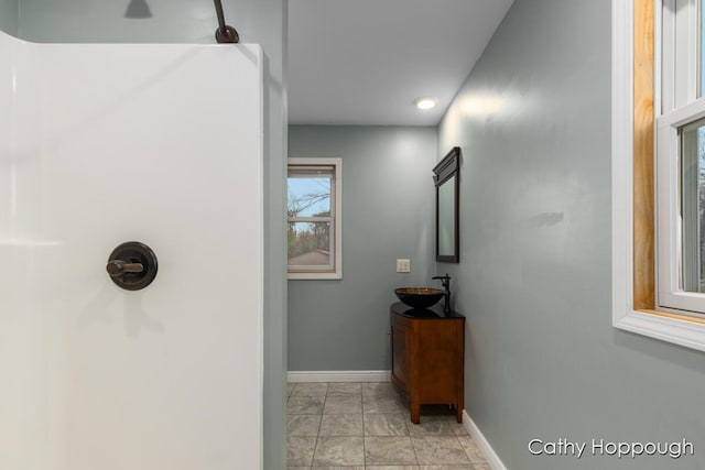 hall with a sink, baseboards, and light marble finish flooring