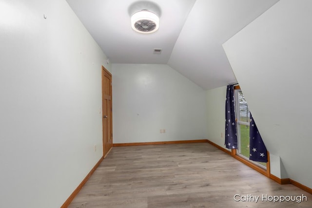 bonus room featuring vaulted ceiling, light wood-type flooring, and baseboards