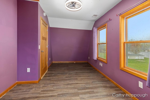 empty room with wood finished floors, baseboards, and vaulted ceiling