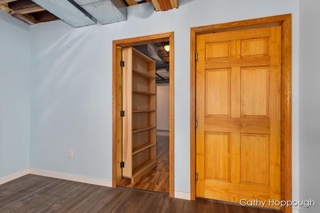unfurnished bedroom with dark wood-type flooring and baseboards
