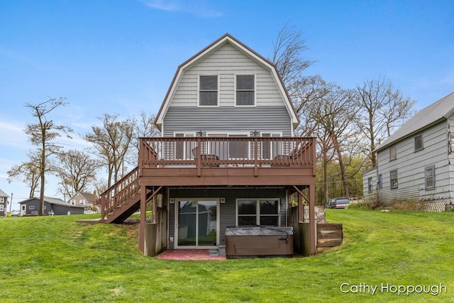 rear view of property featuring a hot tub, a wooden deck, a lawn, and a gambrel roof