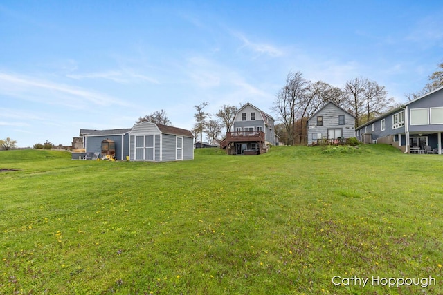 view of grassy yard featuring a storage shed, an outdoor structure, and a wooden deck