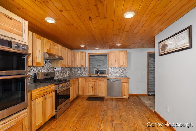 kitchen featuring appliances with stainless steel finishes, under cabinet range hood, wooden ceiling, backsplash, and a sink