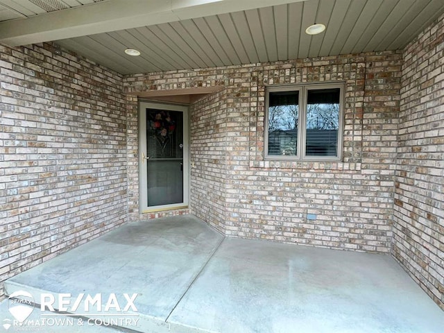 property entrance featuring brick siding and a patio area