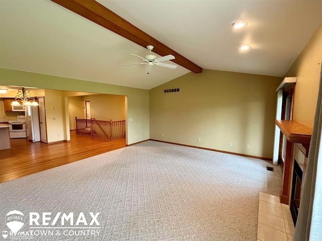 unfurnished living room with light colored carpet, ceiling fan, a fireplace with flush hearth, light wood-style floors, and a chandelier