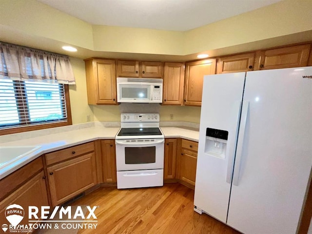 kitchen with white appliances, light wood-style flooring, light countertops, and a sink