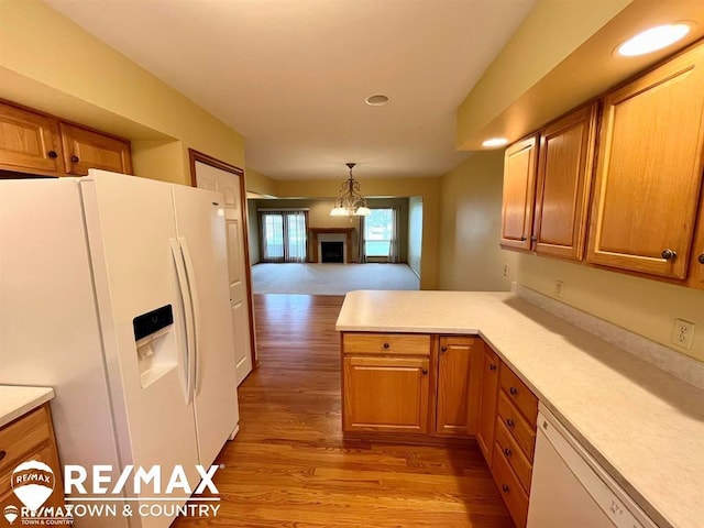 kitchen with white appliances, light wood-style flooring, light countertops, a peninsula, and brown cabinetry