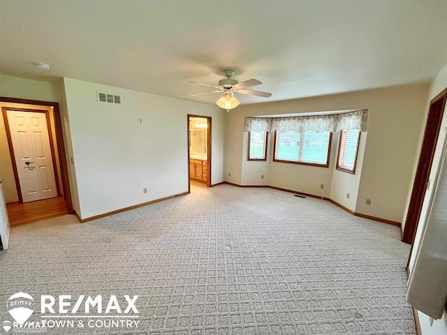 spare room featuring light carpet, a ceiling fan, baseboards, and a smoke detector