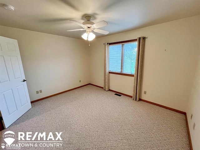 spare room featuring light carpet, a ceiling fan, baseboards, and a smoke detector