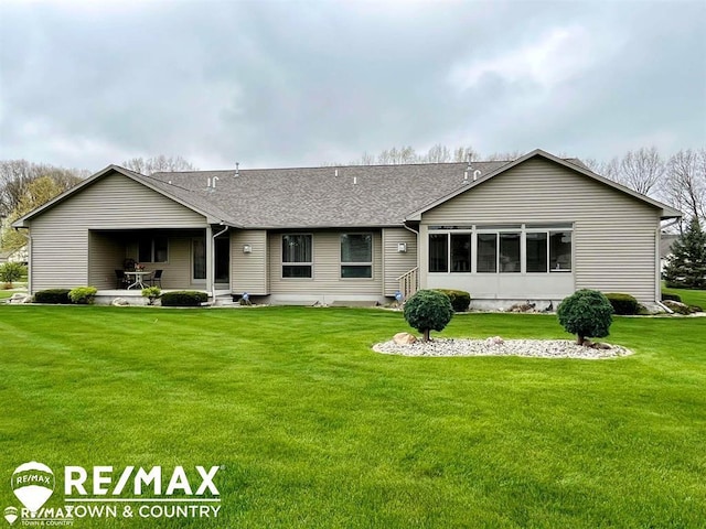 back of property with a lawn and roof with shingles