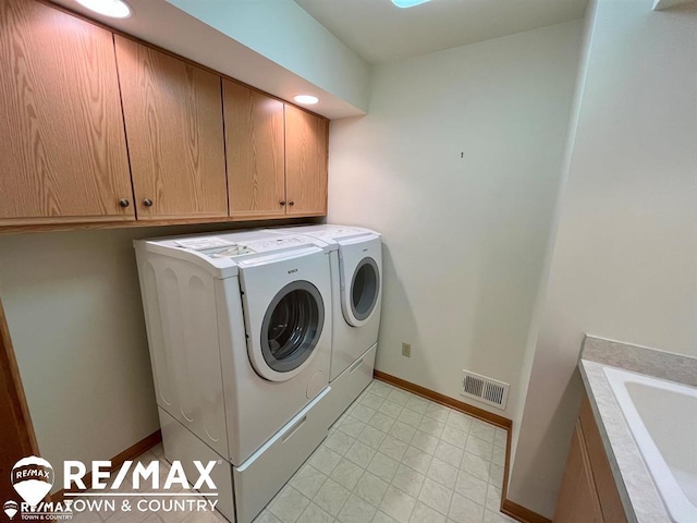 clothes washing area with washer and clothes dryer, baseboards, and cabinet space
