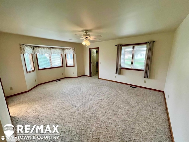 spare room with carpet, a ceiling fan, and baseboards