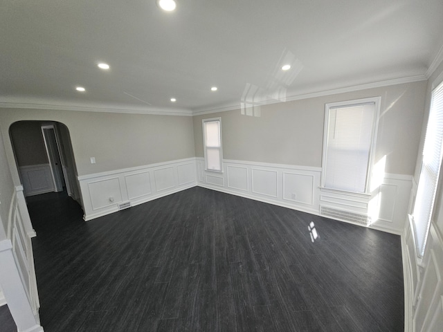 empty room featuring a wainscoted wall, ornamental molding, recessed lighting, arched walkways, and dark wood-style flooring