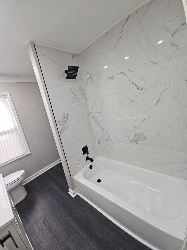 bathroom featuring toilet, shower / washtub combination, wood finished floors, and baseboards