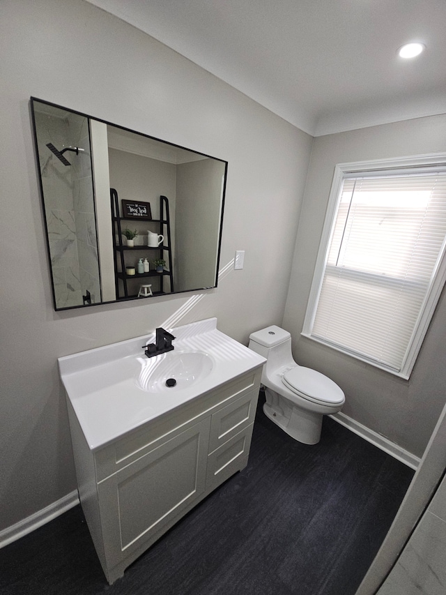 bathroom with vanity, toilet, wood finished floors, and baseboards