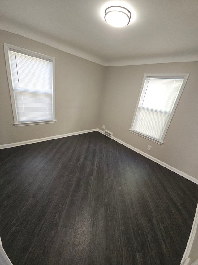 spare room with baseboards and dark wood-type flooring
