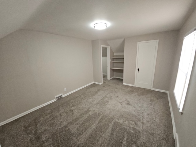 unfurnished bedroom with carpet flooring, vaulted ceiling, and baseboards