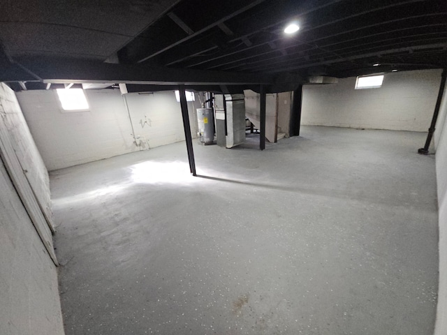 basement featuring heating unit, water heater, and stairs