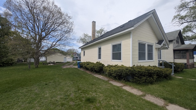 view of side of property with a chimney and a yard
