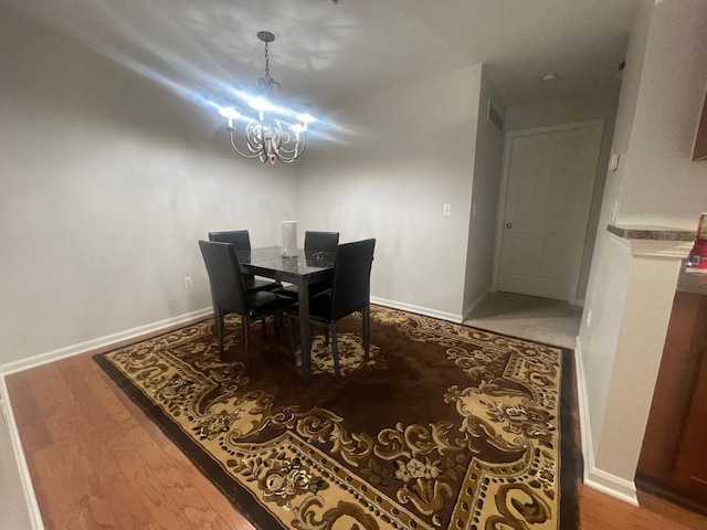 dining space with a chandelier, wood finished floors, and baseboards