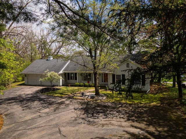 ranch-style home with an attached garage, driveway, and a chimney
