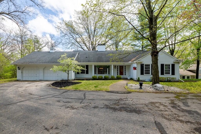 single story home with a garage, asphalt driveway, a chimney, and roof with shingles