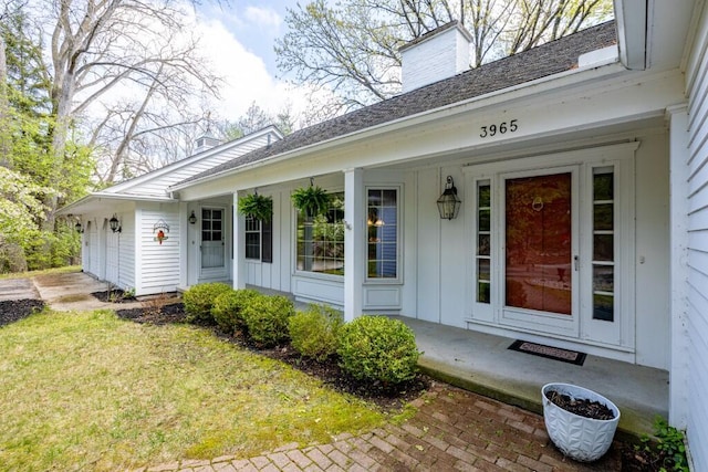 entrance to property featuring a chimney, a porch, board and batten siding, an attached garage, and a shingled roof