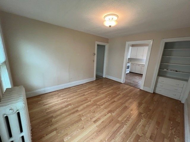475 Saint Clair St, Grosse Pointe, MI 48230 - unfurnished bedroom with light wood-type flooring, baseboards, and radiator heating unit