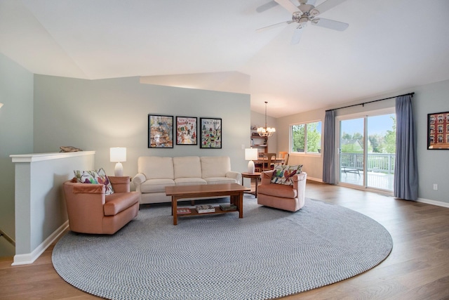 living room featuring lofted ceiling, a chandelier, wood finished floors, baseboards, and ceiling fan