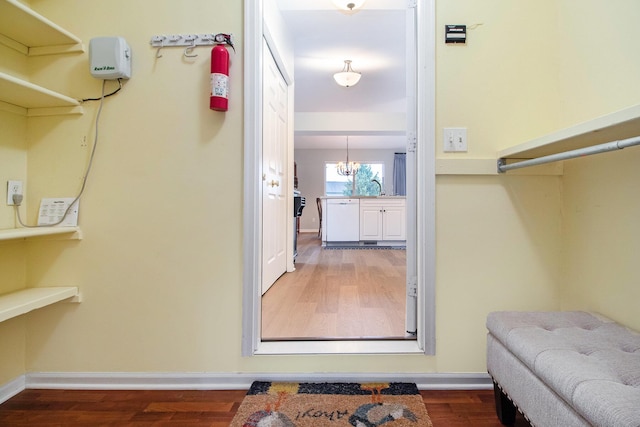 spacious closet with wood finished floors, a sink, and a chandelier