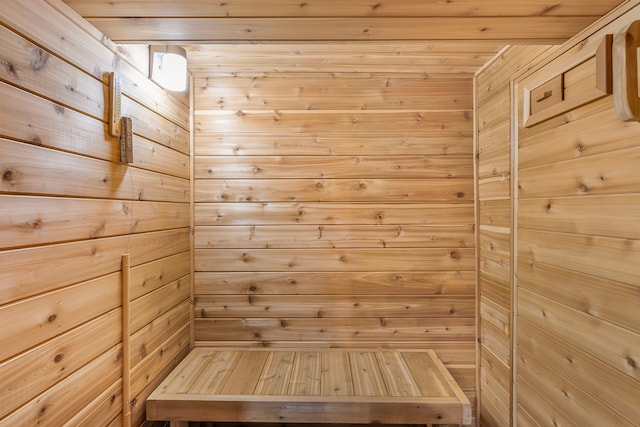 relaxing sauna / steam room featuring wooden ceiling and wood walls