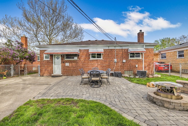 back of property featuring a chimney, brick siding, a fire pit, and a patio