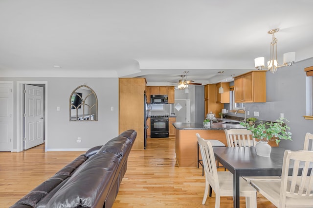 dining room with light wood-style floors, a chandelier, a ceiling fan, and baseboards
