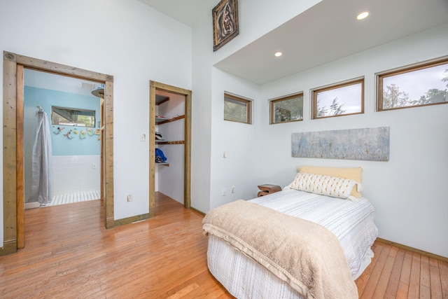 bedroom with light wood finished floors, baseboards, a closet, recessed lighting, and a walk in closet