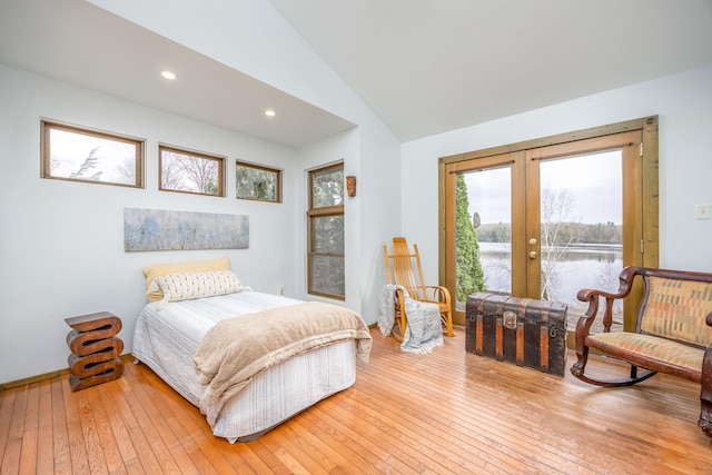 bedroom featuring french doors, hardwood / wood-style floors, access to outside, lofted ceiling, and a water view