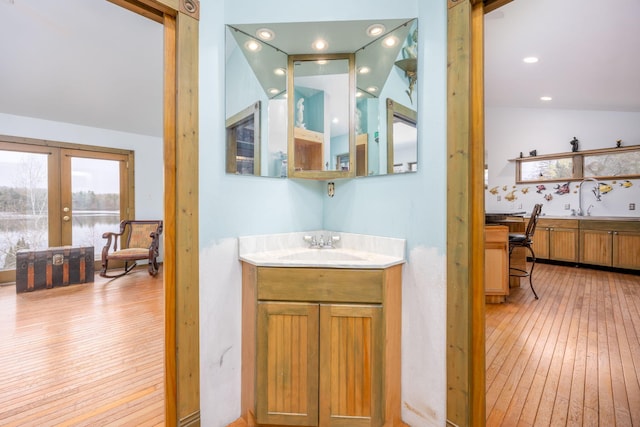 bathroom featuring hardwood / wood-style floors, french doors, vaulted ceiling, and vanity