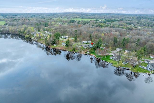aerial view of property's location with a nearby body of water and a heavily wooded area
