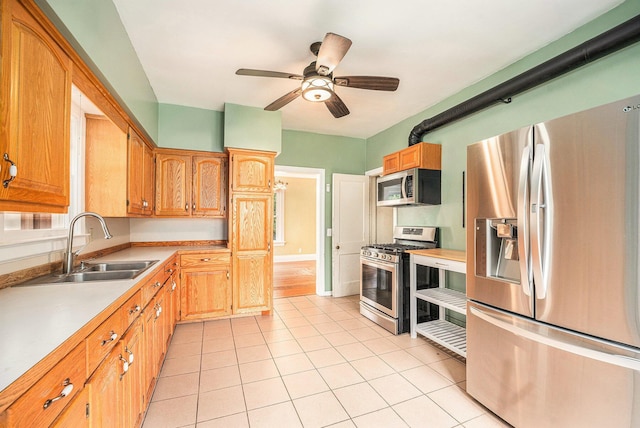 kitchen with appliances with stainless steel finishes, a sink, light tile patterned floors, light countertops, and ceiling fan
