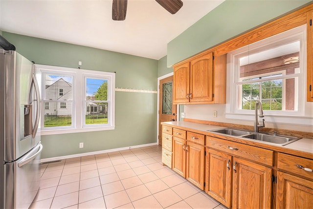 kitchen featuring stainless steel fridge with ice dispenser, a sink, light countertops, a ceiling fan, and light tile patterned floors