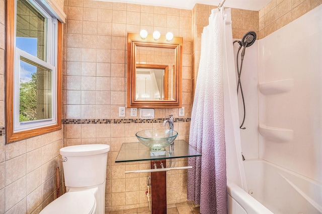 bathroom featuring a sink, tile walls, toilet, and shower / bath combination with curtain