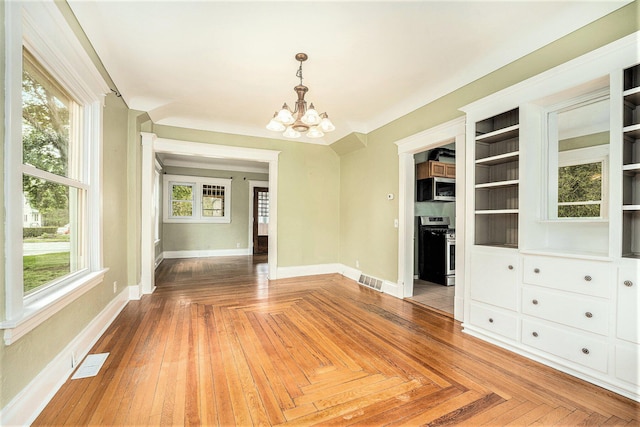 unfurnished dining area with a chandelier, baseboards, and healthy amount of natural light