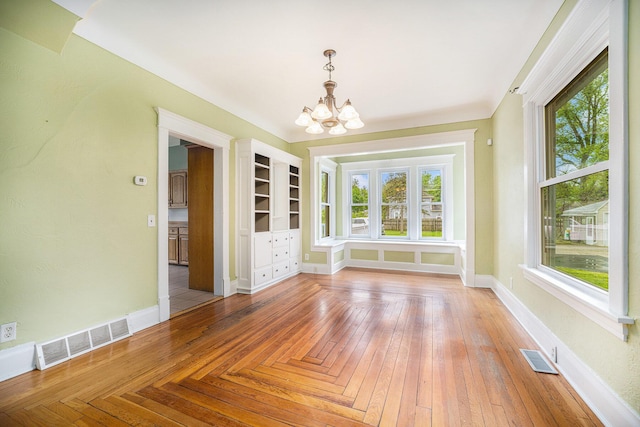unfurnished dining area featuring a chandelier, baseboards, and built in shelves