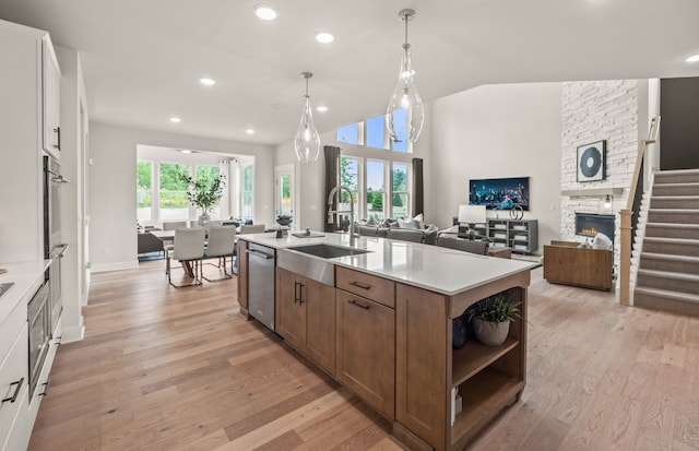 kitchen featuring a sink, stainless steel appliances, light countertops, light wood-style floors, and open floor plan