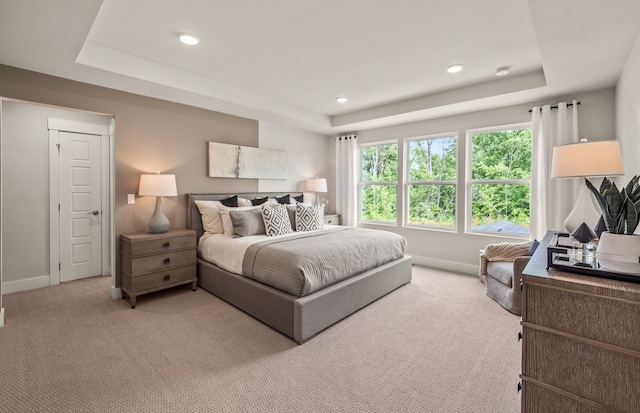 bedroom with a tray ceiling, light carpet, baseboards, and recessed lighting