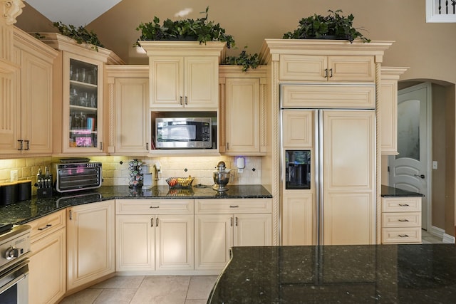 62702 Somerset Blvd, Washington, MI 48094 - kitchen featuring built in appliances, cream cabinets, decorative backsplash, arched walkways, and lofted ceiling