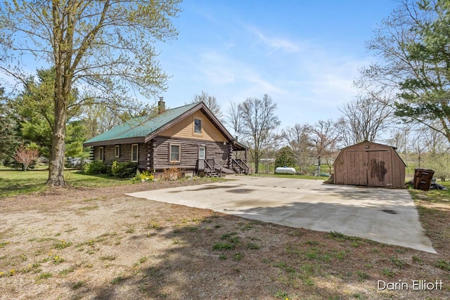5359 Huck Dr, Sheridan, MI 48884 - view of side of property featuring log siding, an outdoor structure, a storage unit, and a chimney