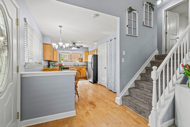 kitchen featuring freestanding refrigerator, a chandelier, light wood-style flooring, pendant lighting, and baseboards
