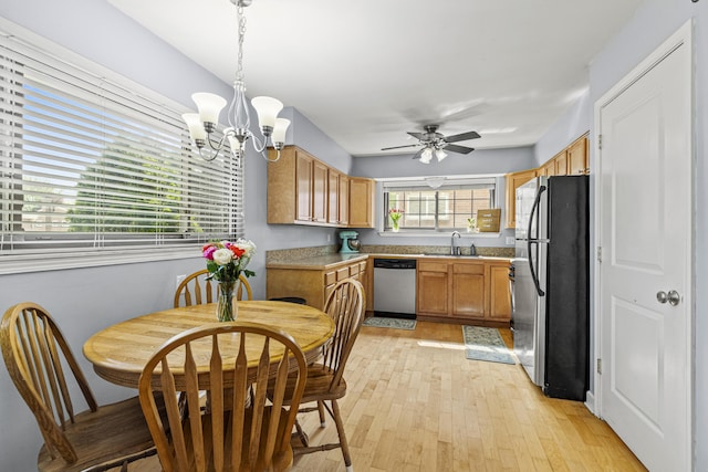 kitchen featuring appliances with stainless steel finishes, a sink, light wood-style flooring, a ceiling fan, and a chandelier