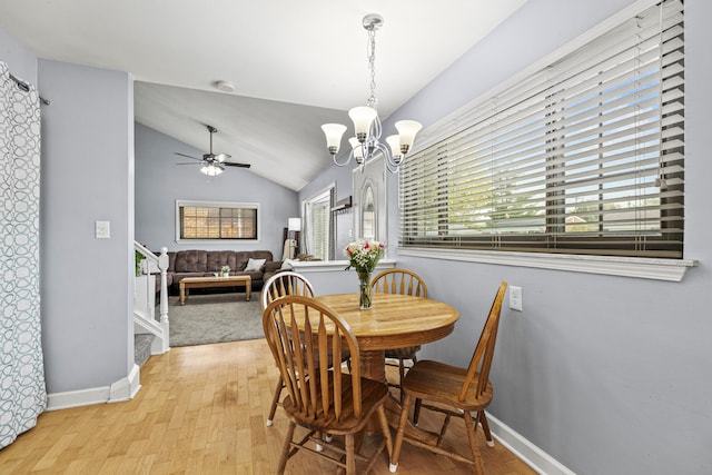 dining space with plenty of natural light, light wood-style floors, a chandelier, vaulted ceiling, and ceiling fan