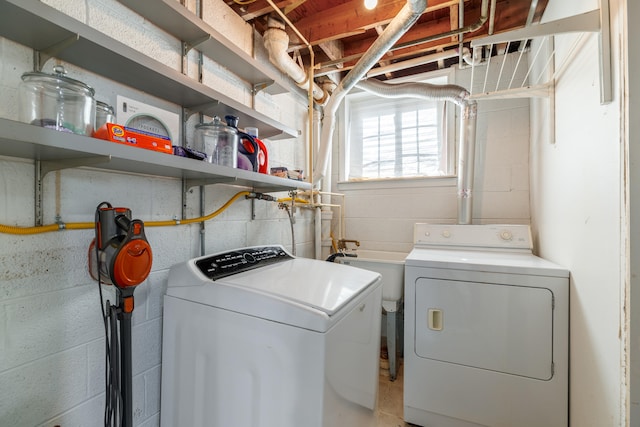clothes washing area featuring washer and clothes dryer and concrete block wall